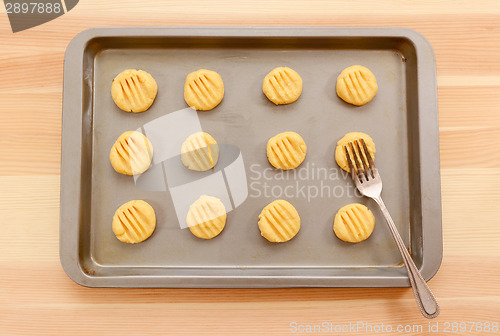 Image of Flattening balls of biscuit dough on a tray