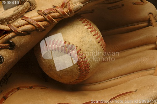 Image of Well-used baseball nestled in a glove.