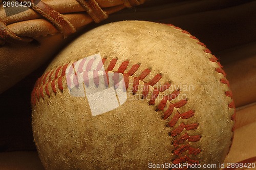 Image of Old well-worn Baseball in a glove.