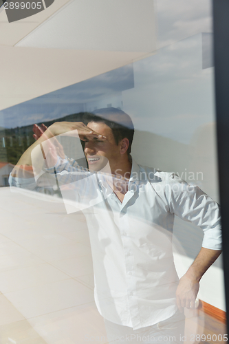 Image of relaxed young man at home on balcony