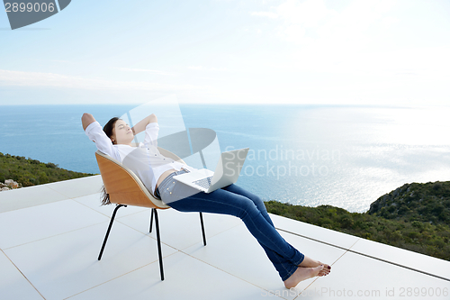 Image of relaxed young woman at home working on laptop