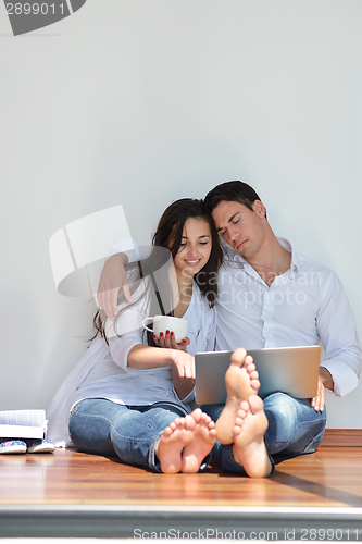 Image of relaxed young couple working on laptop computer at home