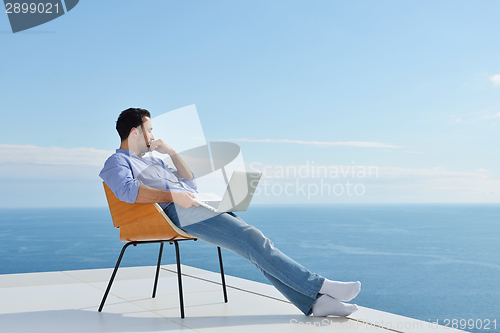 Image of relaxed young man at home on balcony