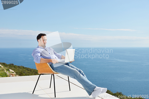 Image of relaxed young man at home on balcony