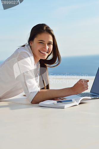 Image of relaxed young woman at home working on laptop computer