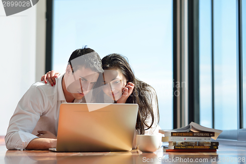 Image of relaxed young couple working on laptop computer at home