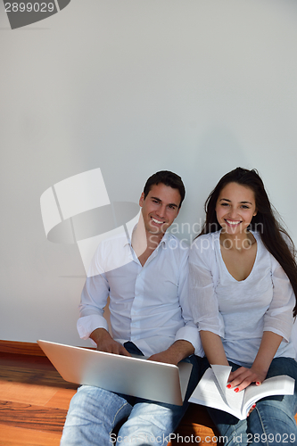 Image of relaxed young couple working on laptop computer at home
