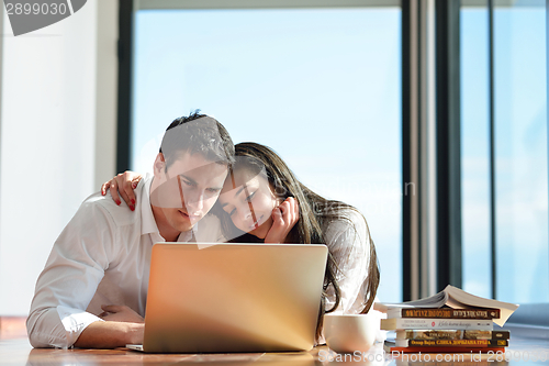 Image of relaxed young couple working on laptop computer at home