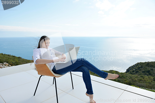 Image of relaxed young woman at home working on laptop