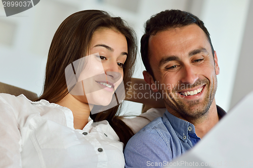 Image of relaxed young couple working on laptop computer at home