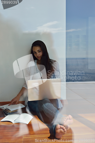 Image of relaxed young woman at home working on laptop computer