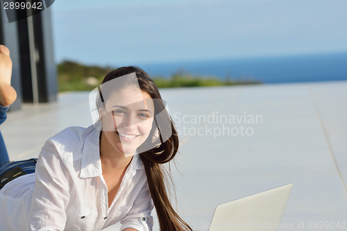 Image of relaxed young woman at home working on laptop computer