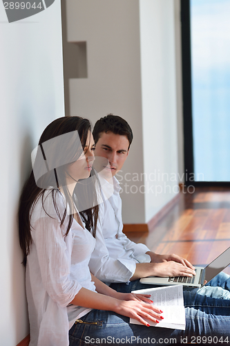 Image of relaxed young couple working on laptop computer at home