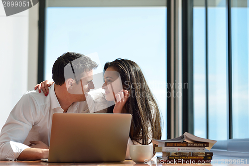 Image of relaxed young couple working on laptop computer at home