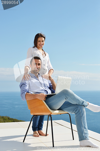 Image of relaxed young couple working on laptop computer at home