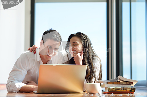 Image of relaxed young couple working on laptop computer at home