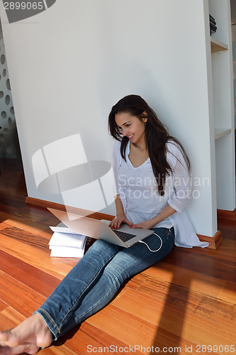Image of relaxed young woman at home working on laptop computer