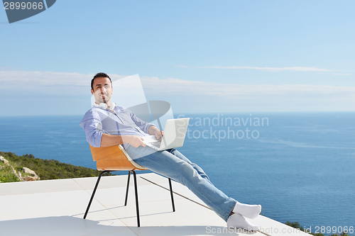 Image of relaxed young man at home on balcony