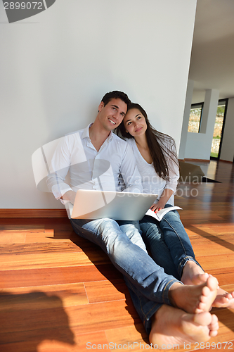 Image of relaxed young couple working on laptop computer at home