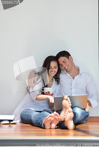Image of relaxed young couple working on laptop computer at home
