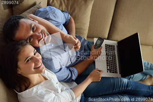 Image of relaxed young couple working on laptop computer at home