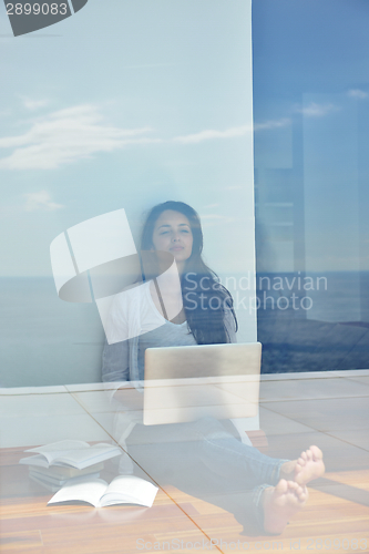 Image of relaxed young woman at home working on laptop computer