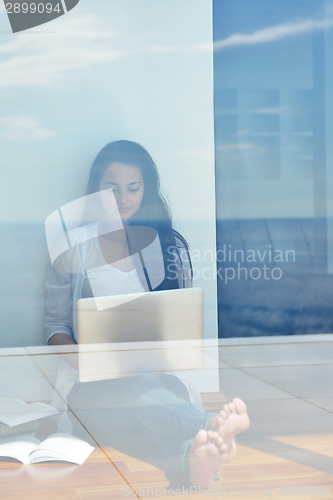 Image of relaxed young woman at home working on laptop computer