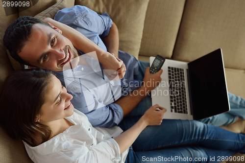 Image of relaxed young couple working on laptop computer at home