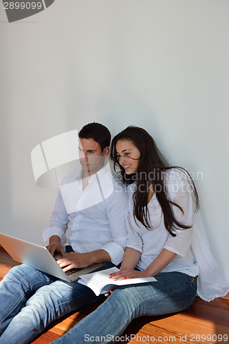 Image of relaxed young couple working on laptop computer at home