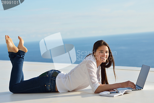 Image of relaxed young woman at home working on laptop computer