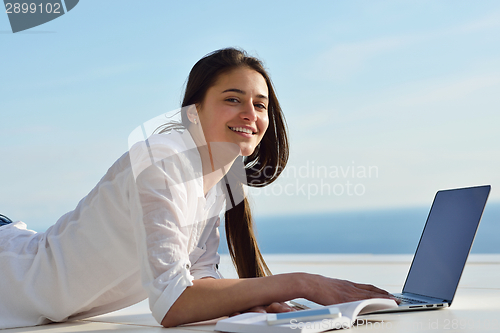 Image of relaxed young woman at home working on laptop computer