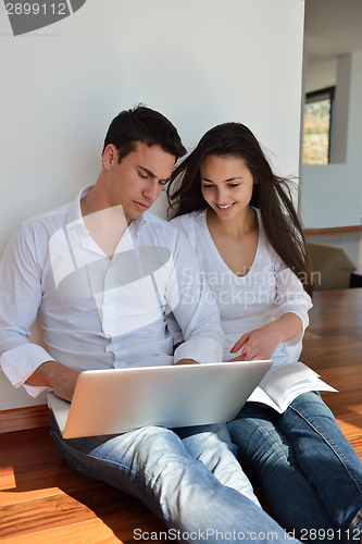 Image of relaxed young couple working on laptop computer at home