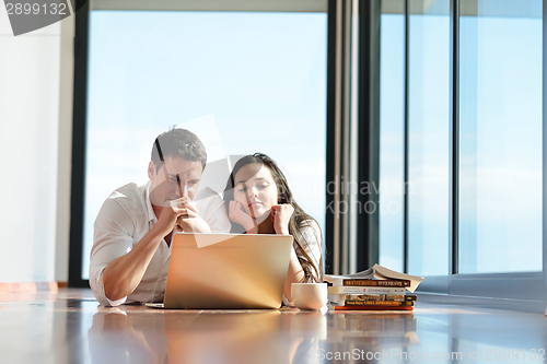 Image of relaxed young couple working on laptop computer at home