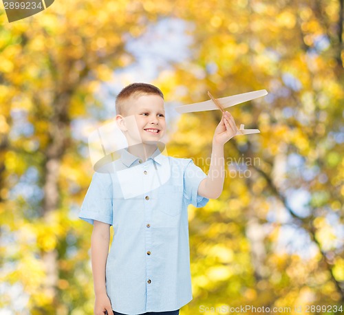 Image of smiling little boy holding a wooden airplane model