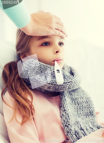 Image of ill girl child with thermometer and caring mother