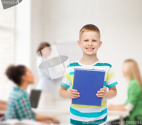 Image of smiling little student boy with blue book