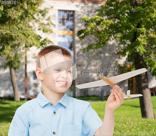 Image of smiling little boy holding a wooden airplane model