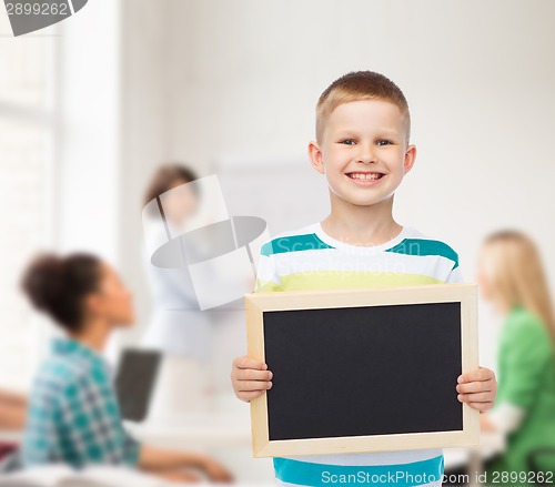 Image of smiling little boy holding blank black chalkboard