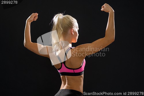 Image of sporty woman from the back flexing her biceps