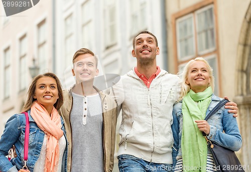 Image of group of smiling friends walking in the city