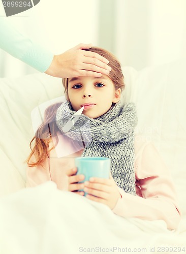 Image of ill girl child with thermometer and caring mother