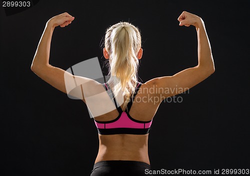 Image of sporty woman from the back flexing her biceps