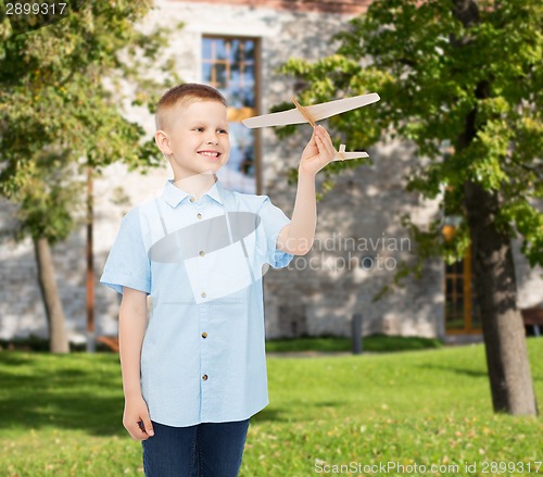 Image of smiling little boy holding a wooden airplane model