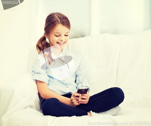 Image of smiling girl with smartphone at home