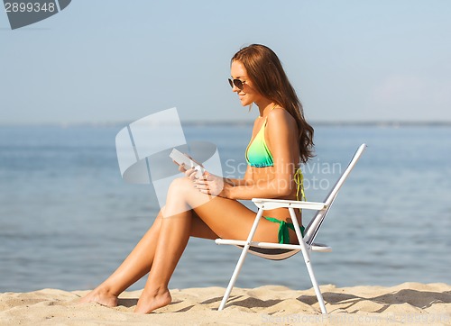 Image of smiling young woman sunbathing in lounge on beach