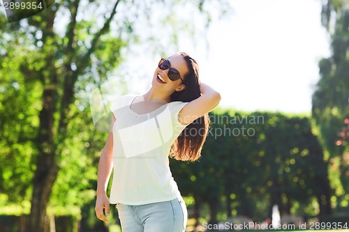 Image of smiling young woman with sunglasses in park