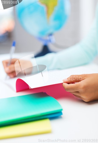 Image of close up of young woman writing in workbook