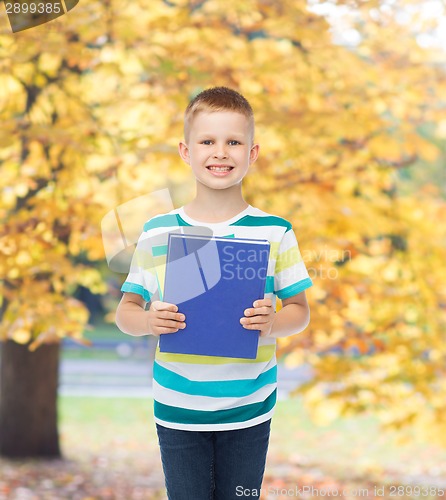 Image of smiling little student boy with blue book