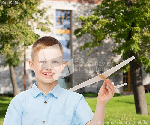 Image of smiling little boy holding a wooden airplane model