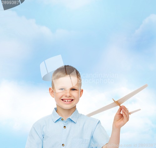 Image of smiling little boy holding a wooden airplane model